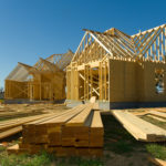 New home under construction with wood, trusses and supplies against blue sky